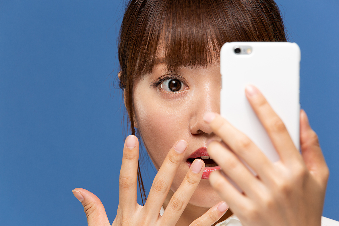 Kvinna tittar förskräckt in i en mobiltelefon.