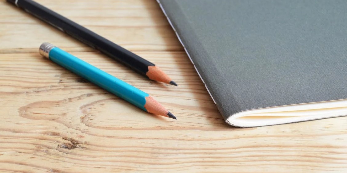 Två pennor och ett skrivblock som ligger på ett bord