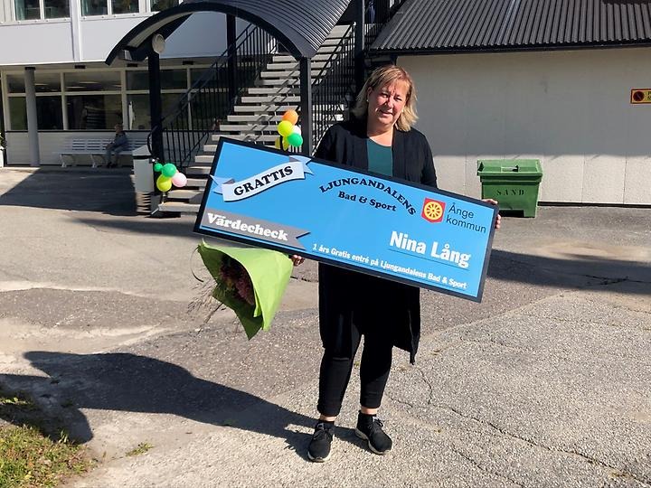 Nina Lång håller i en presentcheck på gratis bad i ett år som hon vann i en namntävling.