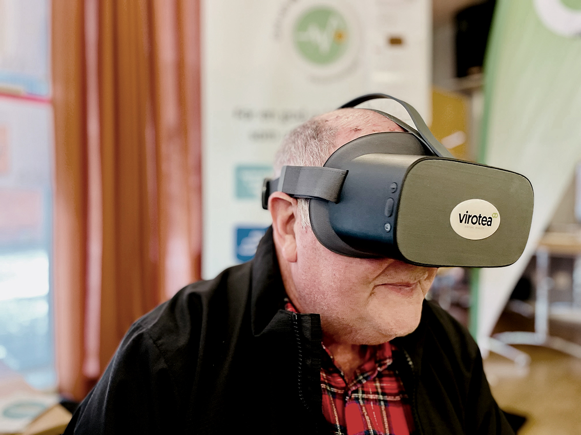 Äldre man sitter med VR-glasögon på huvudet.